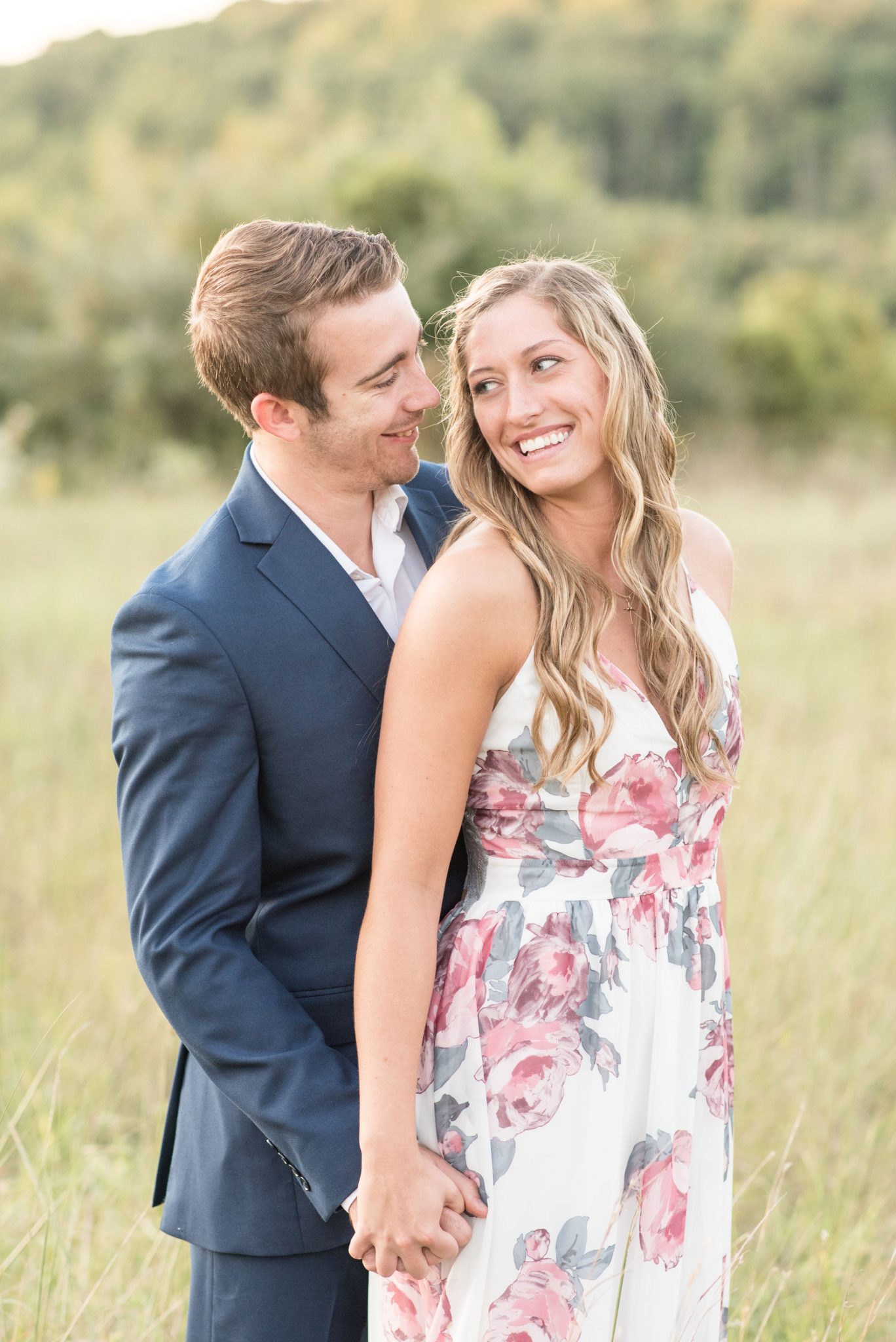Couple look into each other's eyes in grassy field during engagement session by Victoria Rayburn