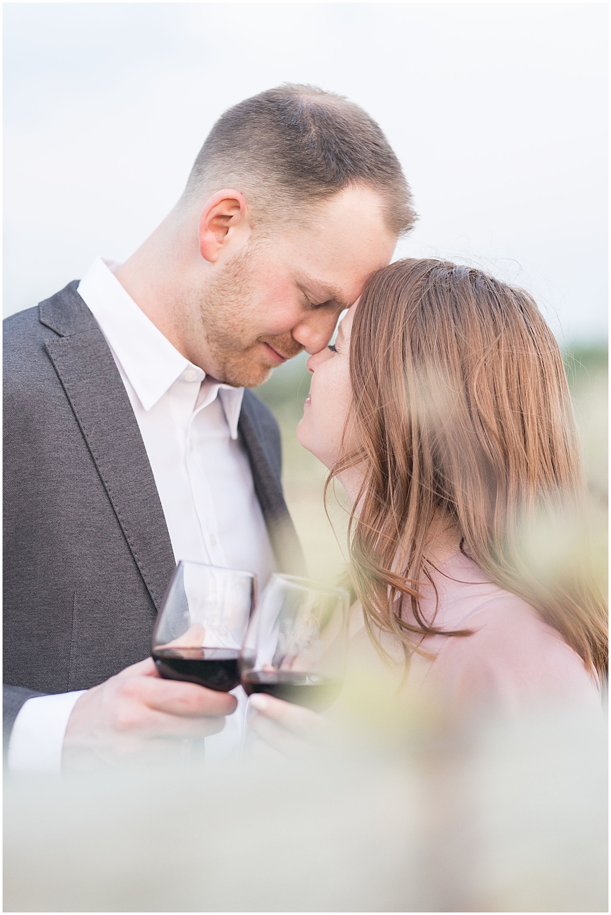 Couple touch foreheads while drinking wine during engagement photos by Indianapolis wedding photographer Victoria Rayburn Photography