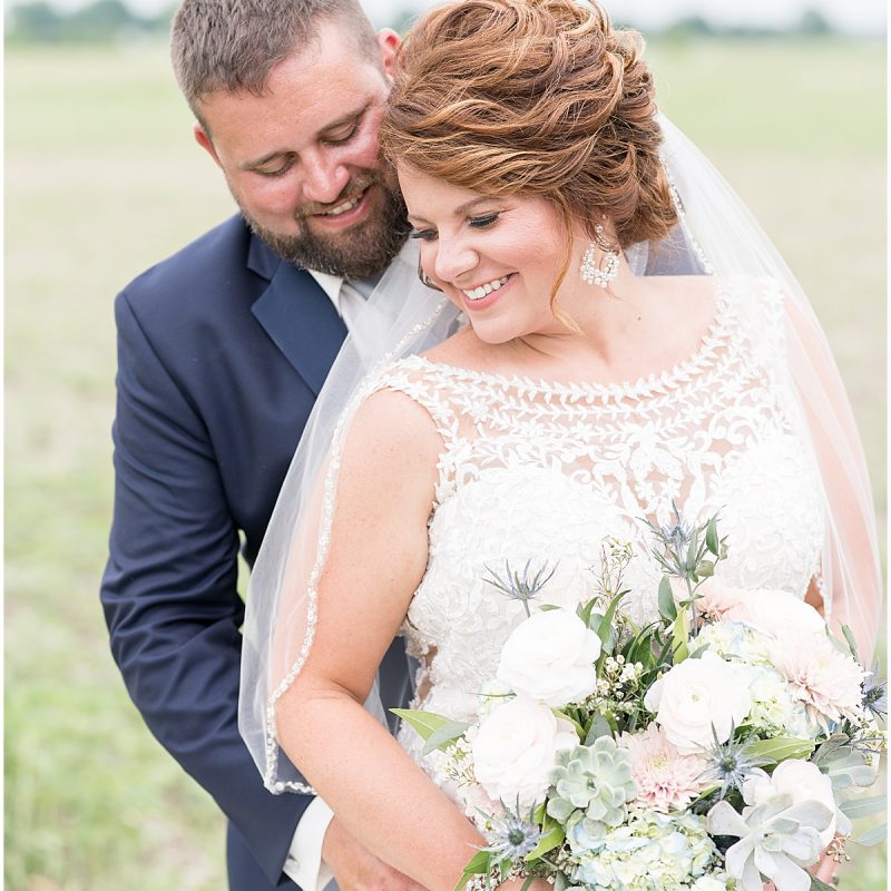 Bride and groom hugging in field after wedding by Indianapolis wedding photographer Victoria Rayburn Photography