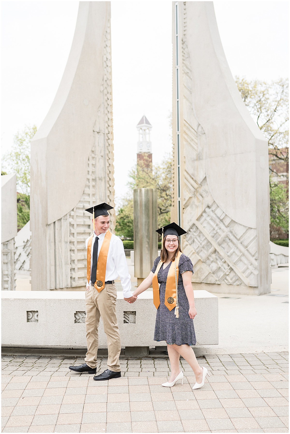 Couple holding hands with caps during engagement photos by Purdue's Engineering Fountain