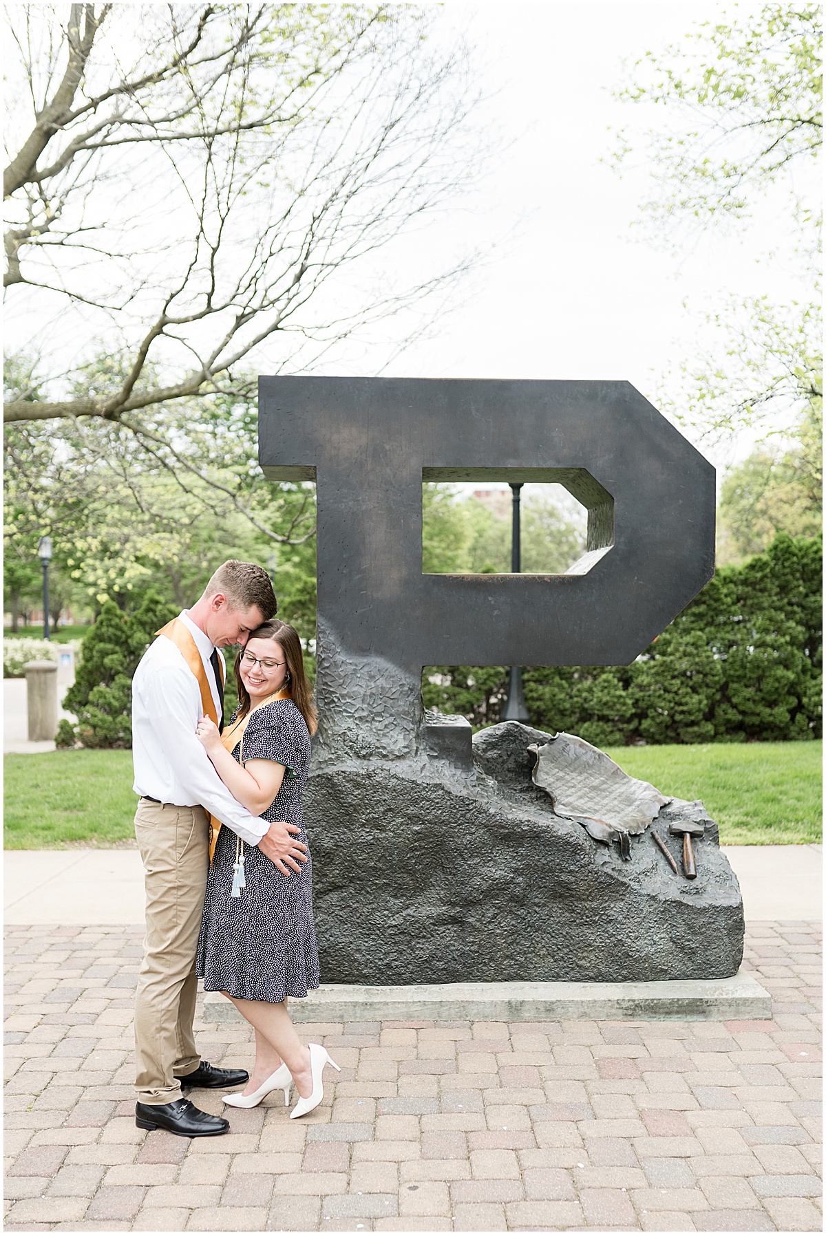 Couple hug with graduation tassles during graduation photos at Purdue University in front of the Purdue Memorial Union