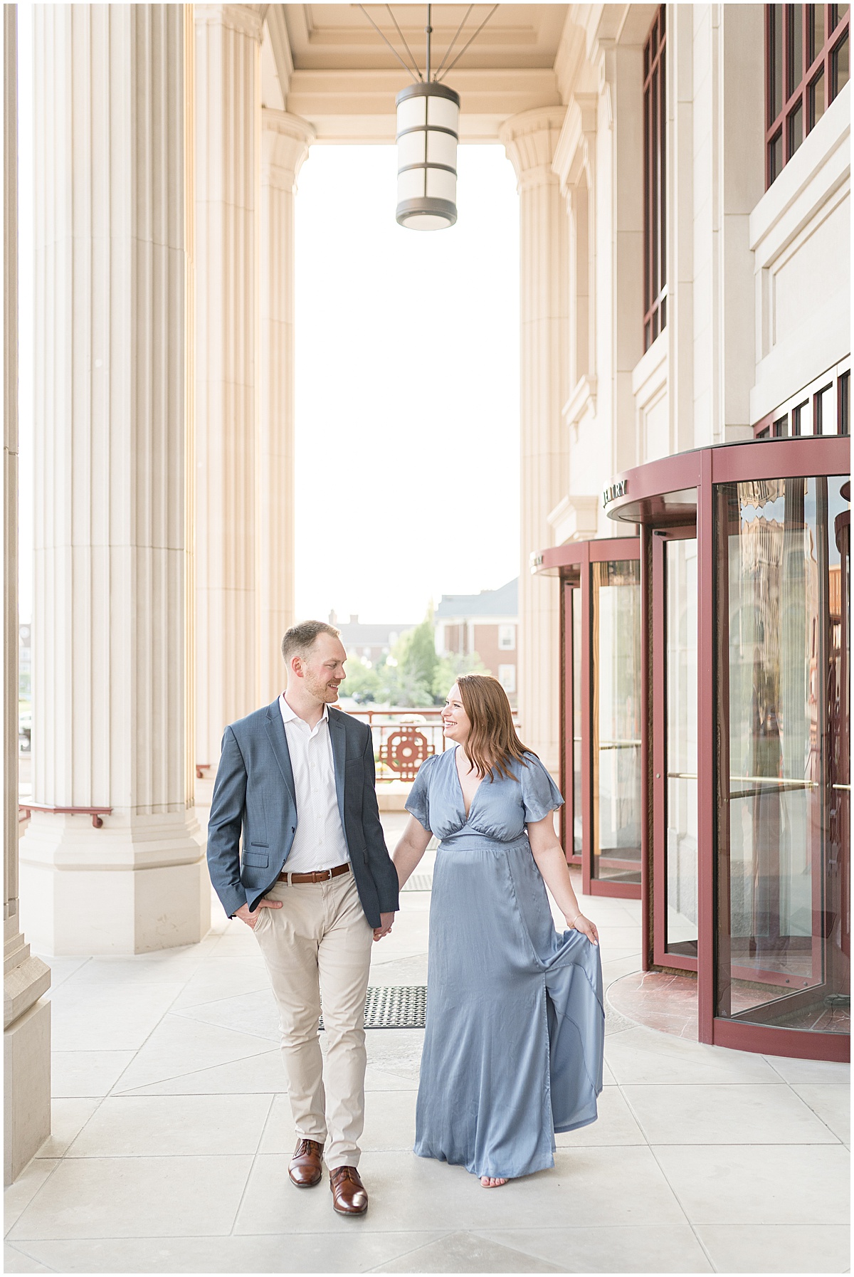 Couple walk holding hands during engagement photos at The Palladium in Carmel, Indiana