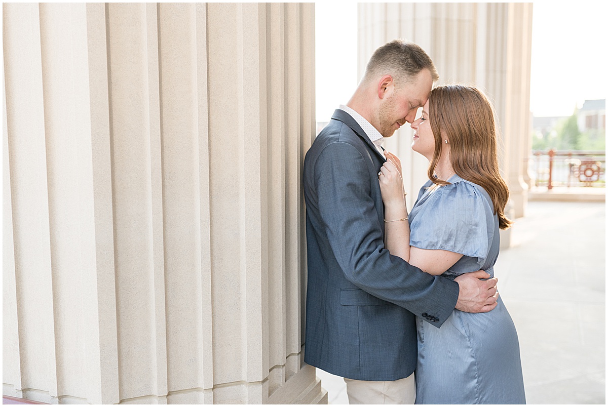 Couple embrace by pillar during engagement photos at The Palladium in Carmel, Indiana