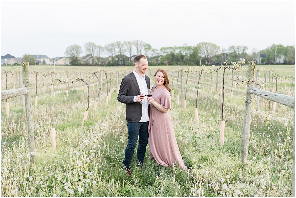 Couple cheers in vineyard during engagement photos at Urban Vines in Carmel, Indiana