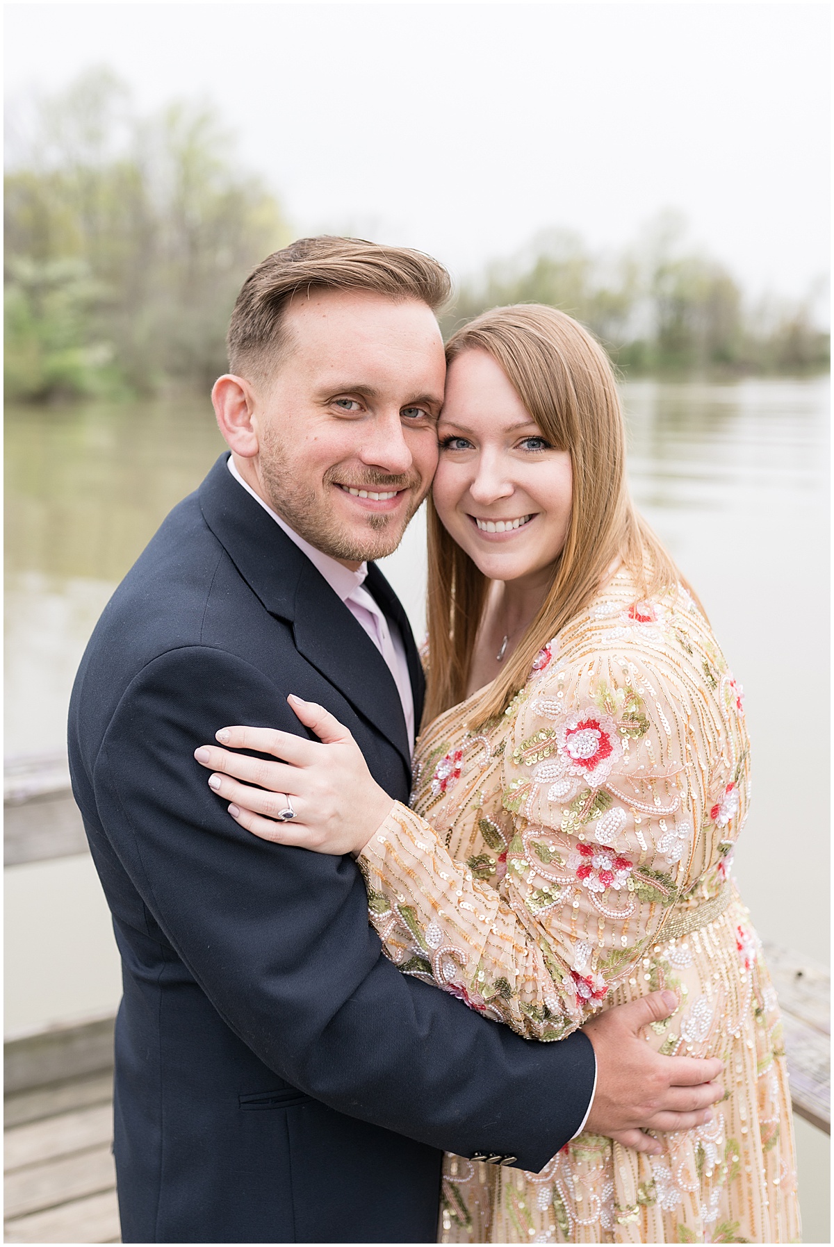Couple by water during early spring engagement photos at Wildcat Creek Reservoir Park in Kokomo, Indiana