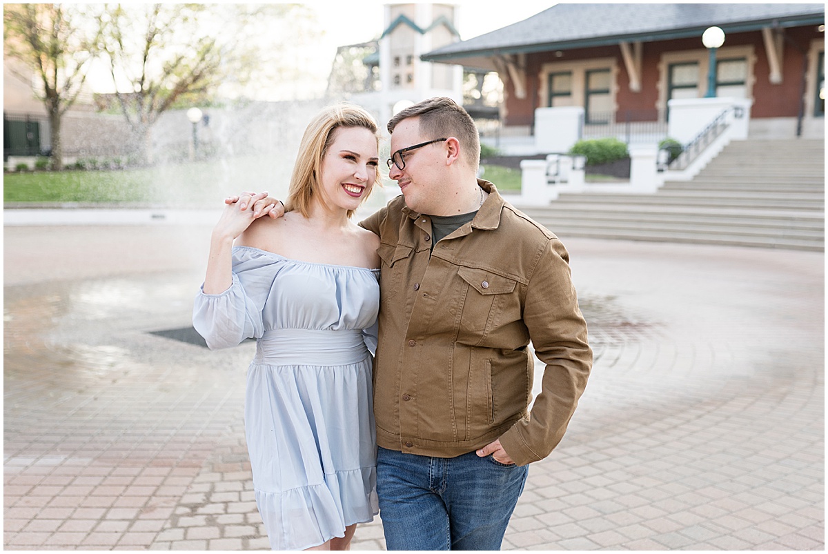 Couple by fountain at spring engagement photos in Downtown Lafayette, Indiana