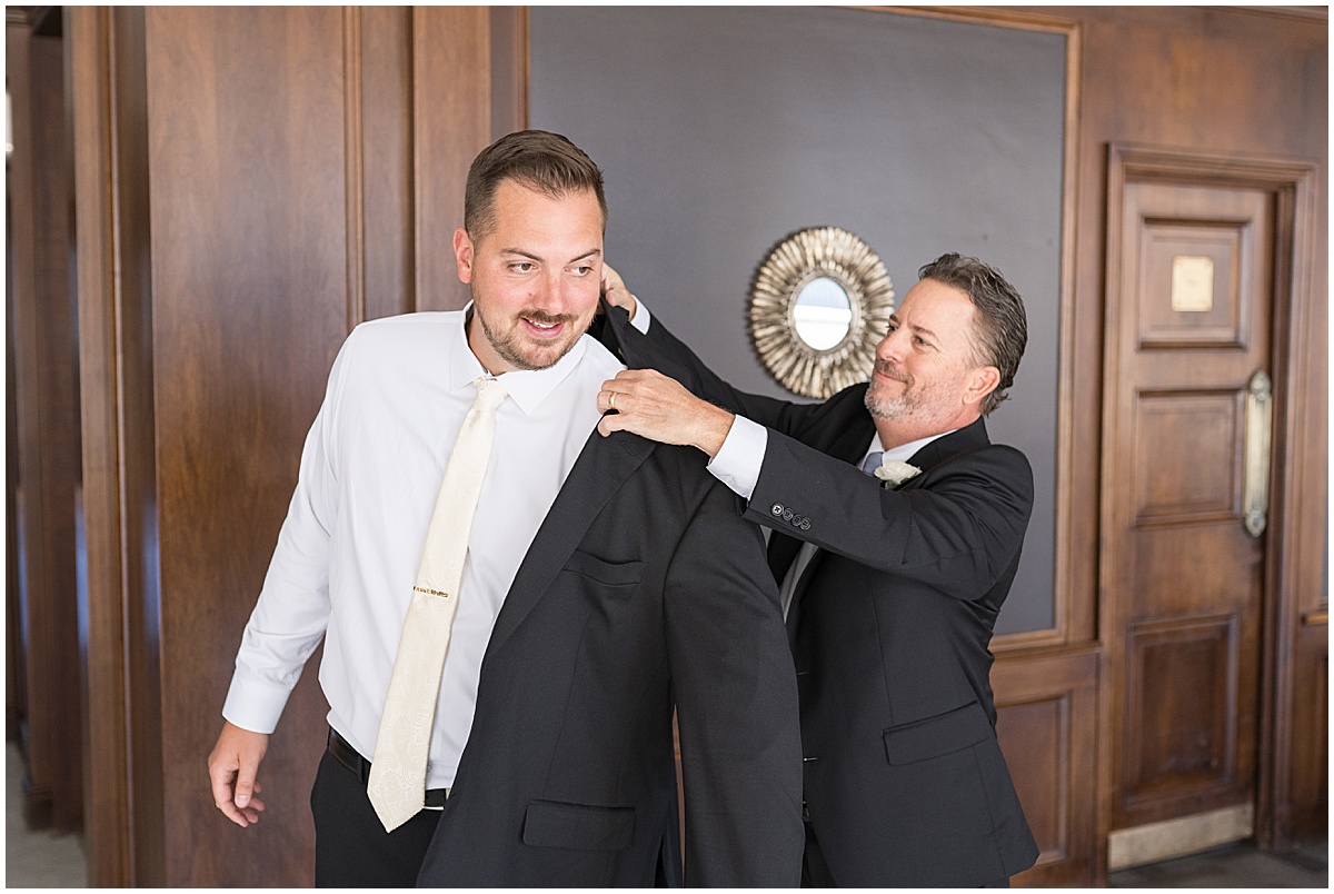 Groom putting on jacket for wedding at JPS Events in downtown Indianapolis.