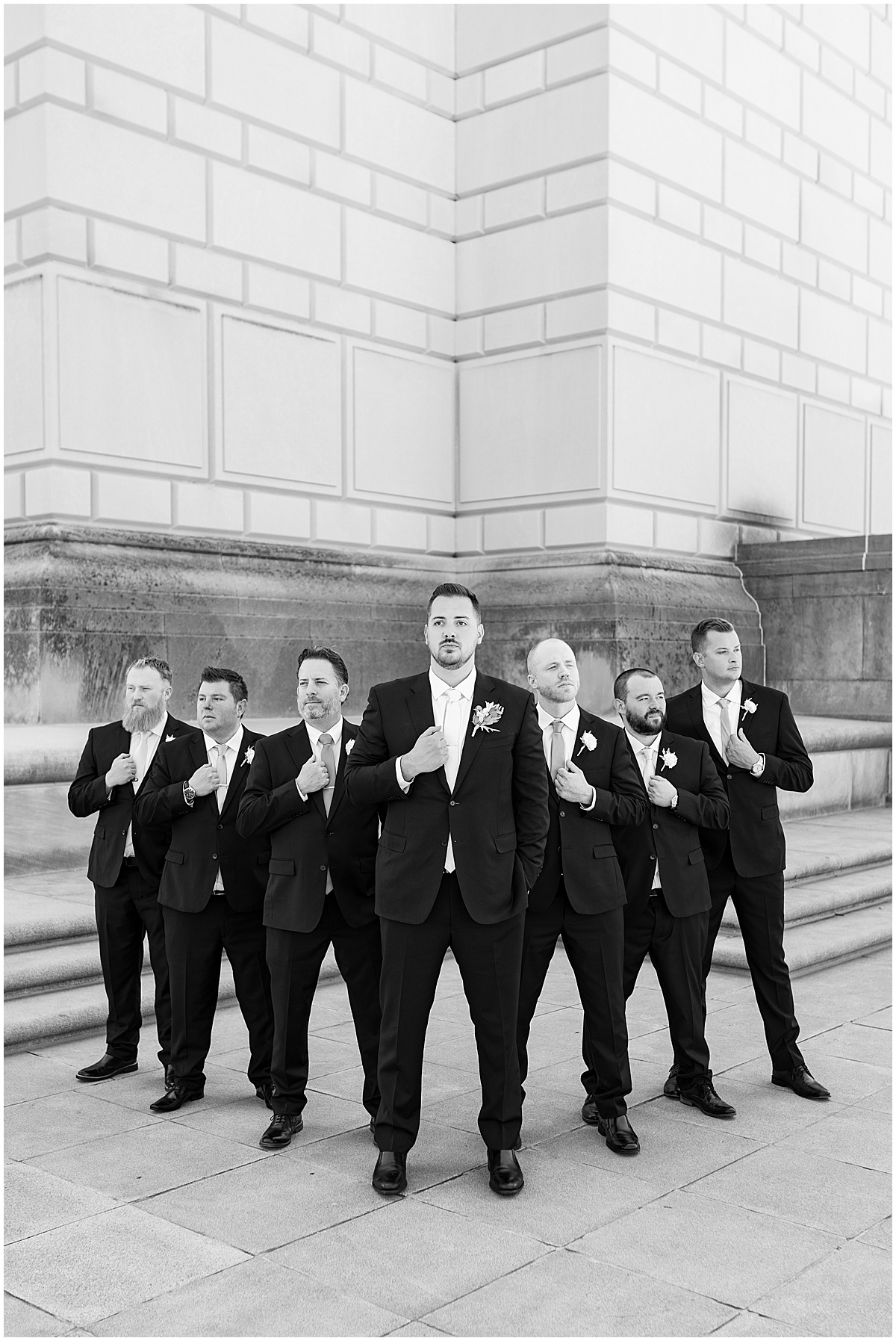 Groom with groomsmen holding jackets at The Indiana War Memorial in downtown Indianapolis.