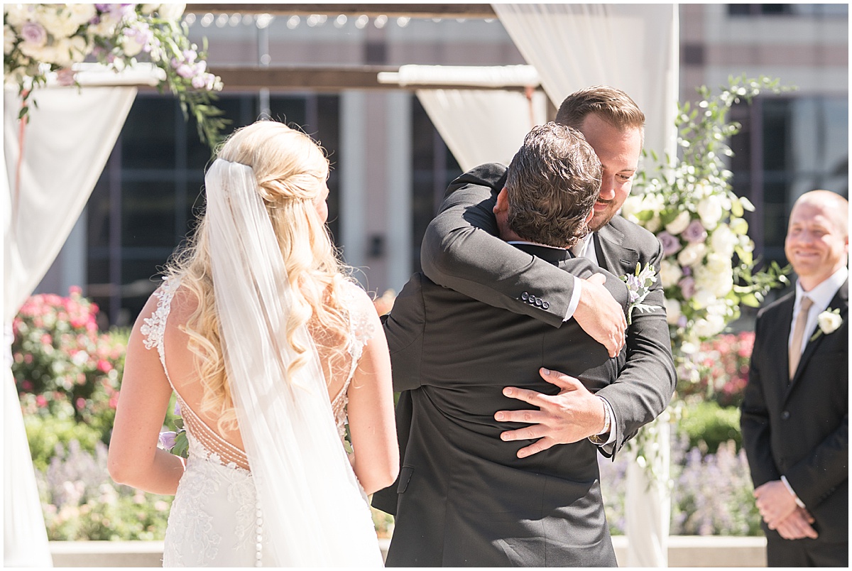 Groom hugging father of the bride at rooftop wedding in downtown Indianapolis at JPS Events