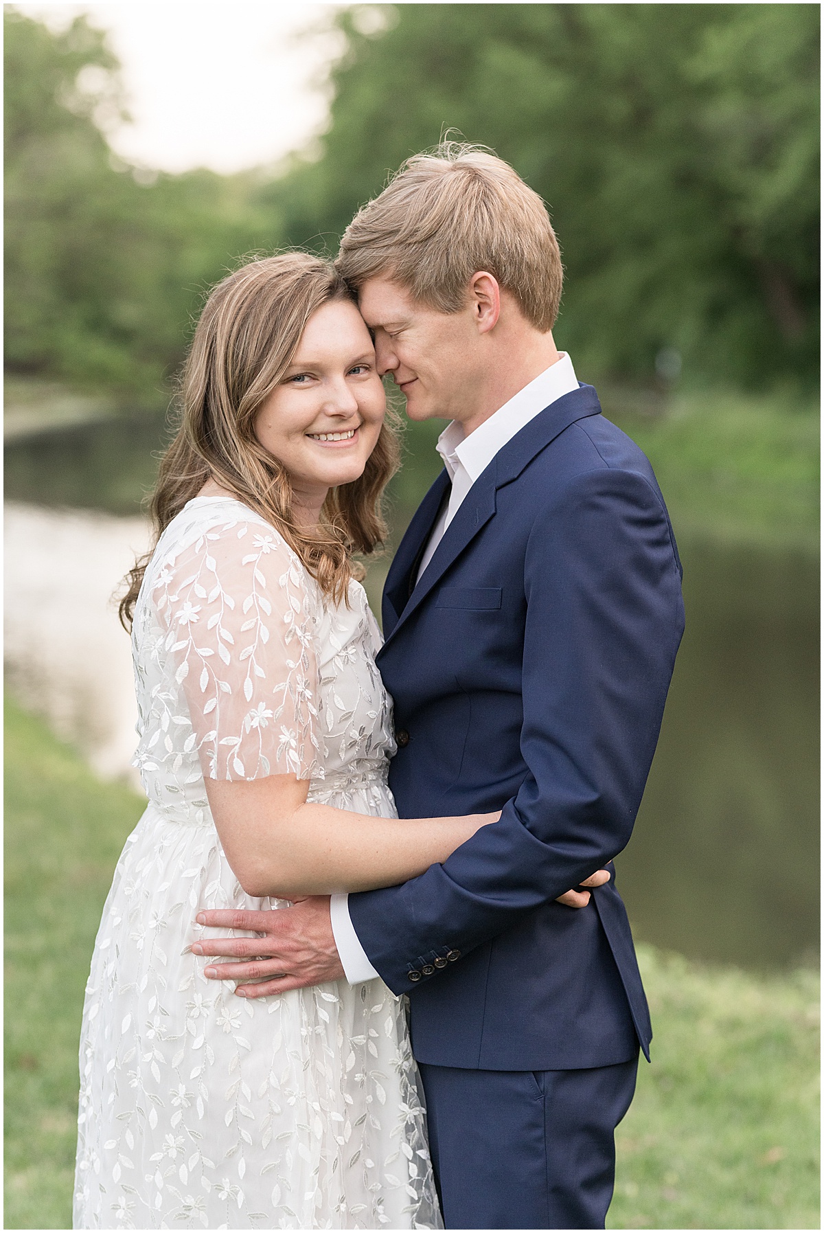 Couple hugging by water at spring engagement photos at Holcomb Gardens in Indianapolis