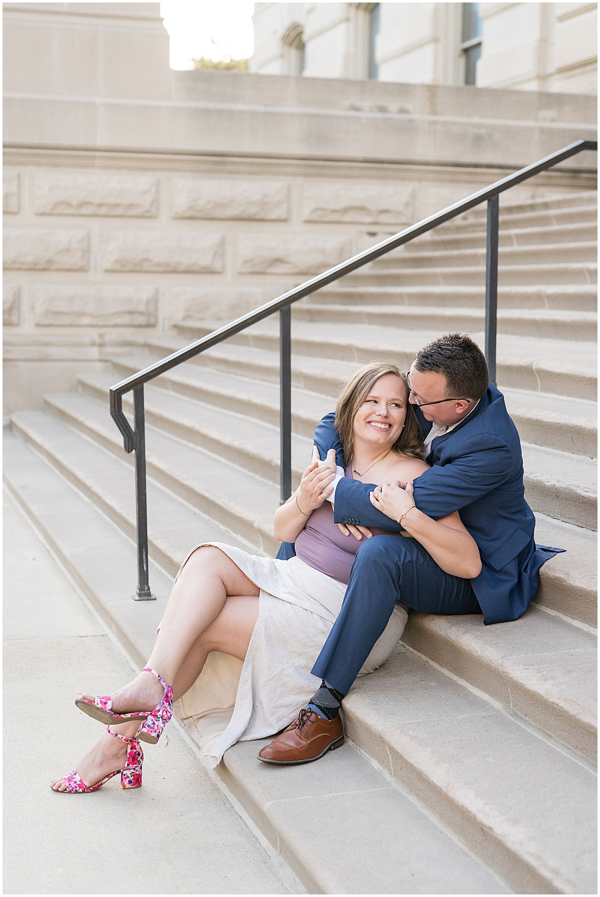Couple sitting on steps during engagement photos in downtown Indianapolis by the Indiana State Capitol Building.