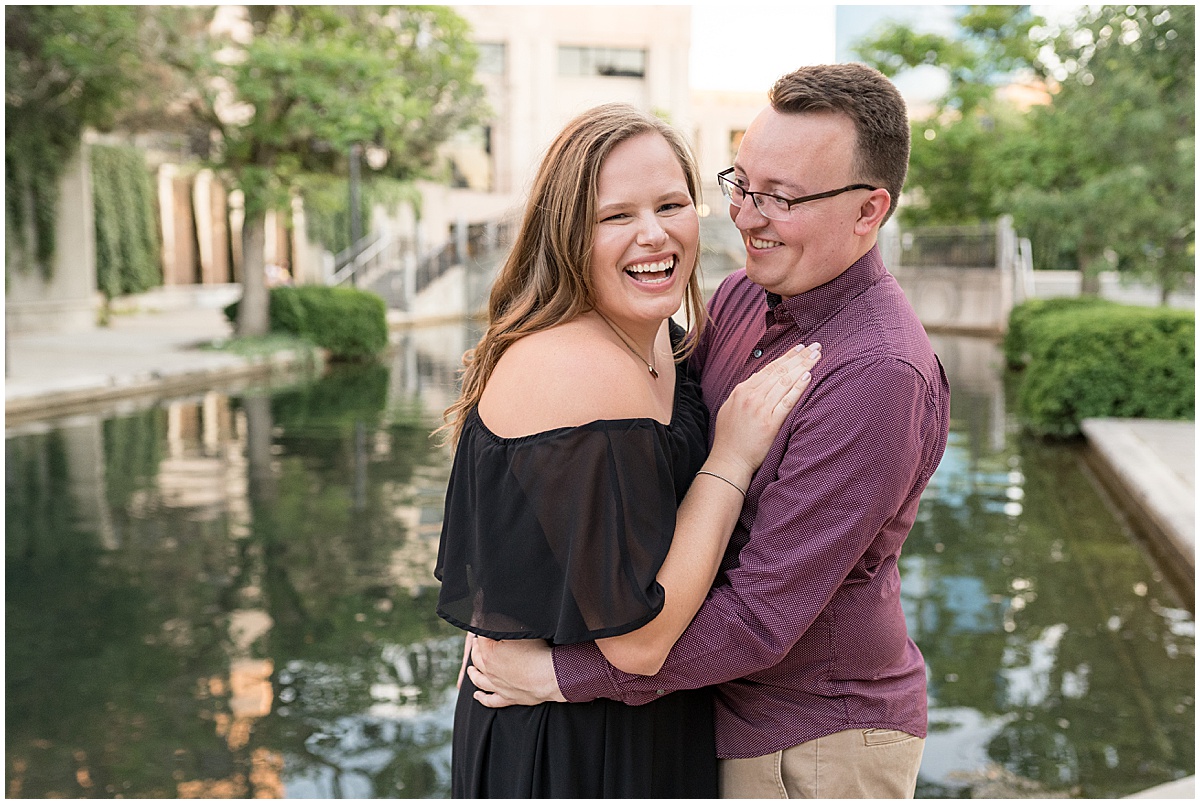 Couple laughing at downtown Indianapolis Canal Walk engagement photos.
