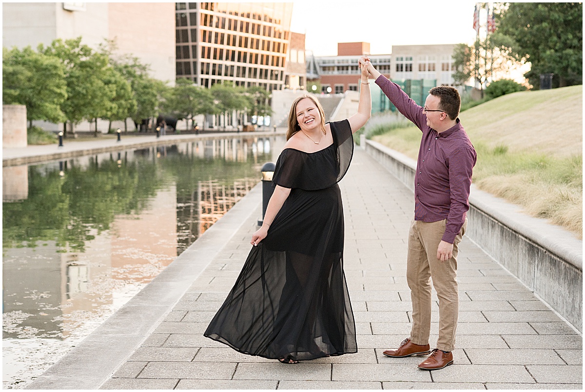 Couple dancing by water during downtown Indianapolis Canal Walk engagement photos.