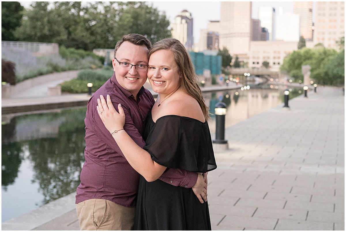 Couple holding eachother close at downtown Indianapolis Canal Walk engagement photos.