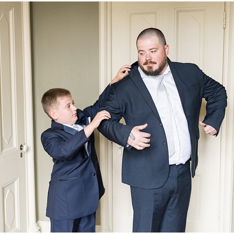 Groom putting on suit jacket before wedding at Fowler House Mansion