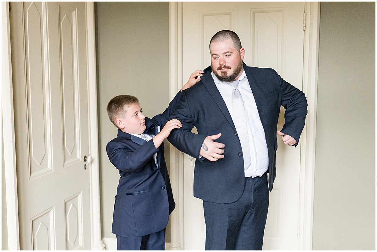 Groom putting on suit jacket before wedding at Fowler House Mansion