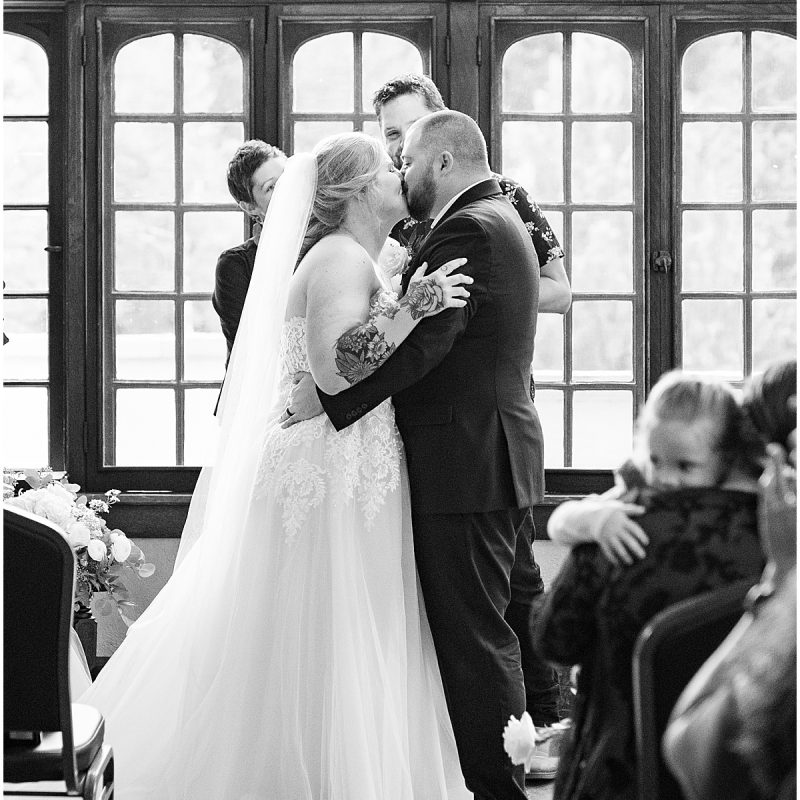 Bride and groom kiss during ceremony at Fowler House Mansion