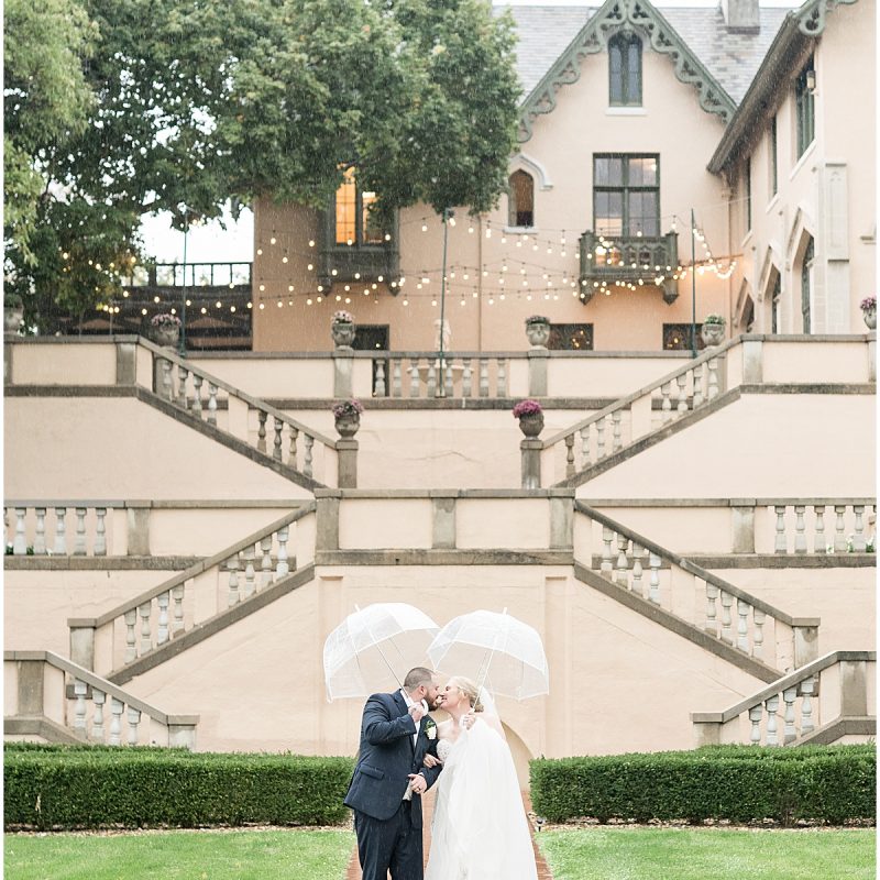 Bride and groom kiss in the rain outside Fowler House Mansion wedding