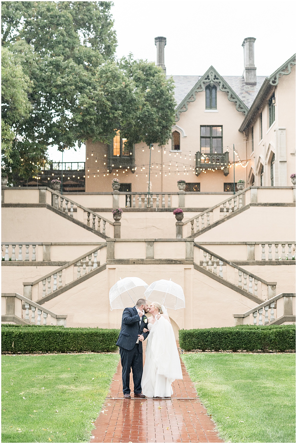 Bride and groom kiss in the rain outside Fowler House Mansion wedding
