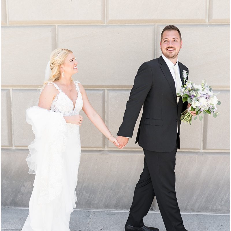Bride and groom walk during wedding photos at at The Indiana World War Memorial in Downtown Indianapolis