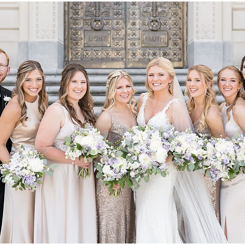 Bride with bridesmaids laughing during wedding photos at at The Indiana World War Memorial in Downtown Indianapolis