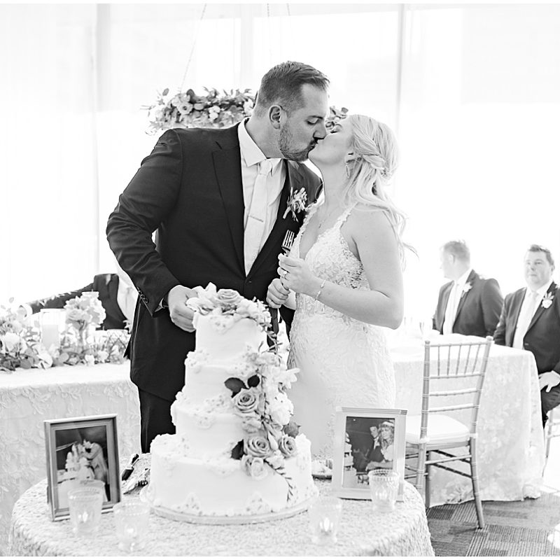 Bride and groom kiss in front of wedding cake at JPS Events Wedding Reception in Downtown Indianapolis