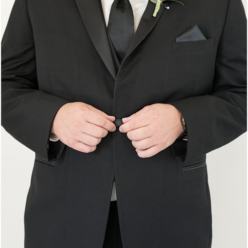 Groom buttoning jacket at New Journey Farms