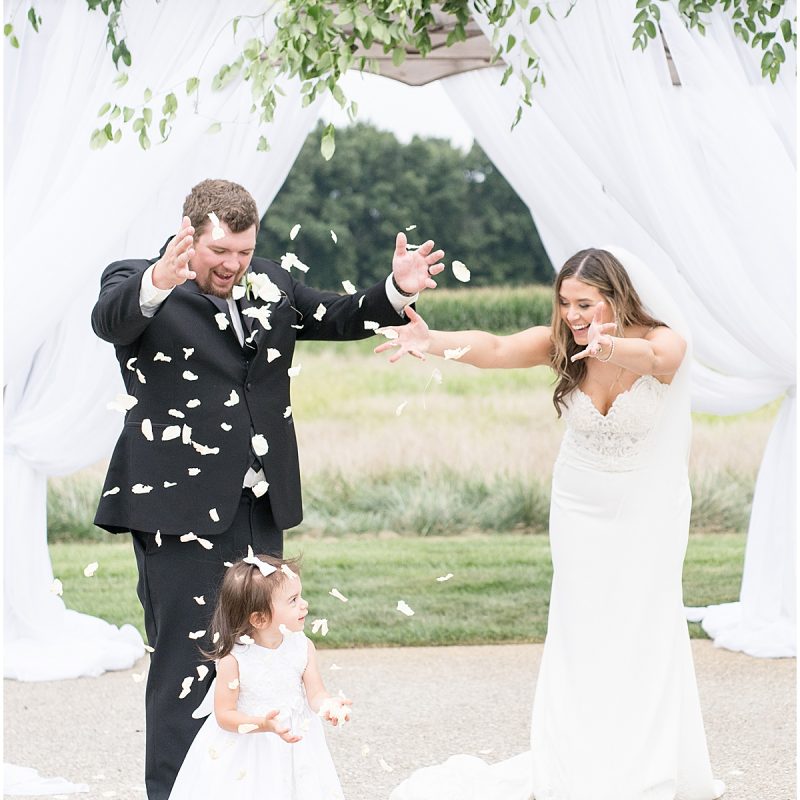 Bride and groom toss flower petals with flower girl at New Journey Farms Wedding