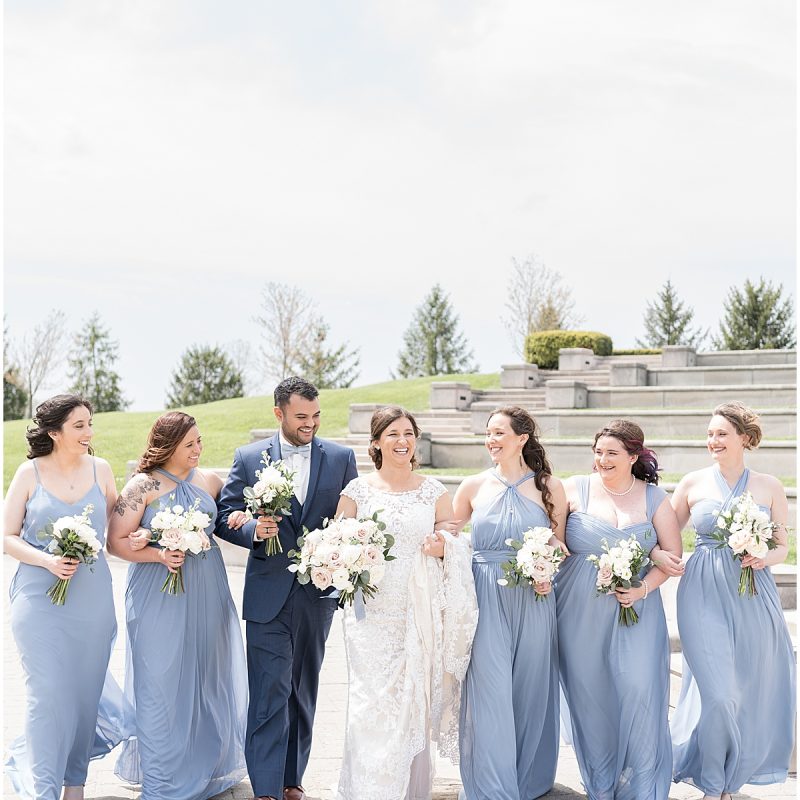 Bride and bridal party walk together during wedding photos at Coxhall Gardens
