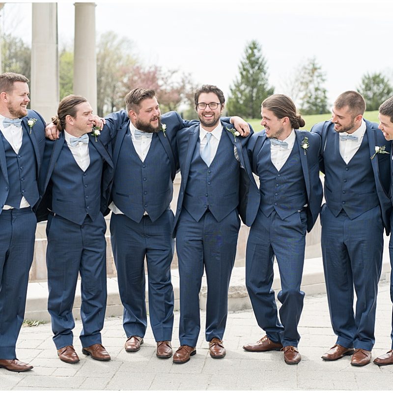 Groom and groomsmen huddle during wedding photos at Coxhall Gardens