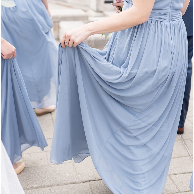 Bridesmaid holds up dress during wedding photos at Coxhall Gardens