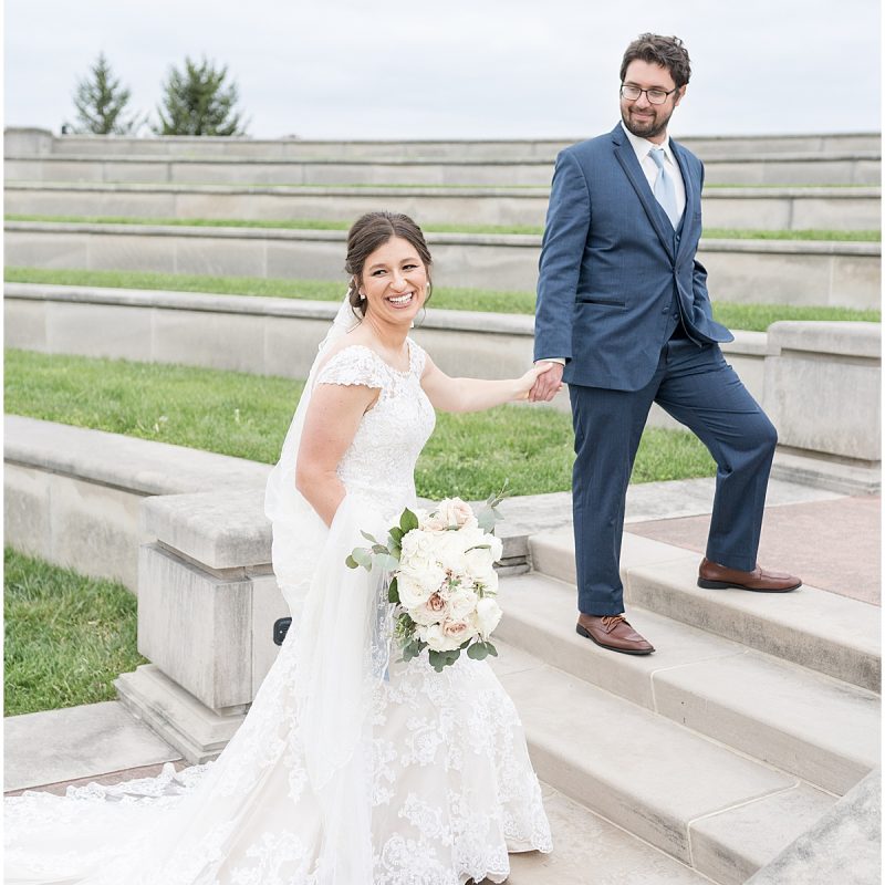 Newlyweds walk up steps during wedding photos at Coxhall Gardens