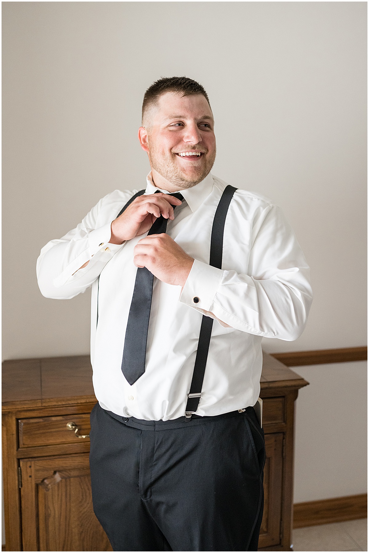 Groom putting on tie for wedding in Converse, Indiana