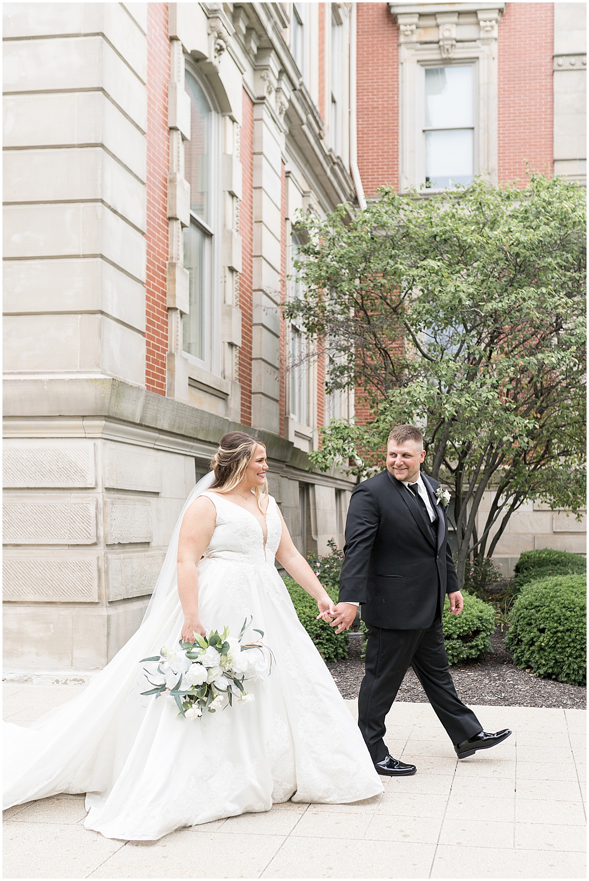 Newlyweds walking during wedding photos at Hamilton County Courthouse in downtown Noblesville, Indiana 
