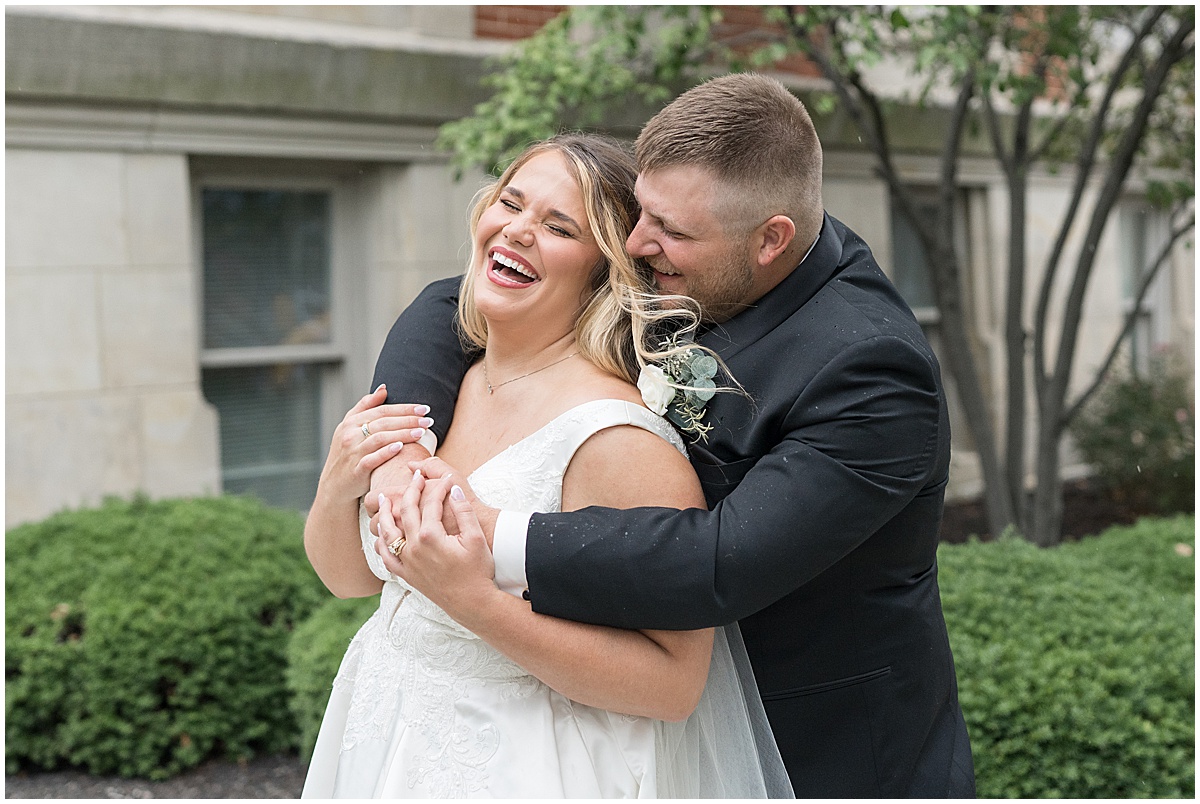 Bride and groom laugh at wedding photos at Hamilton County Courthouse in downtown Noblesville, Indiana 