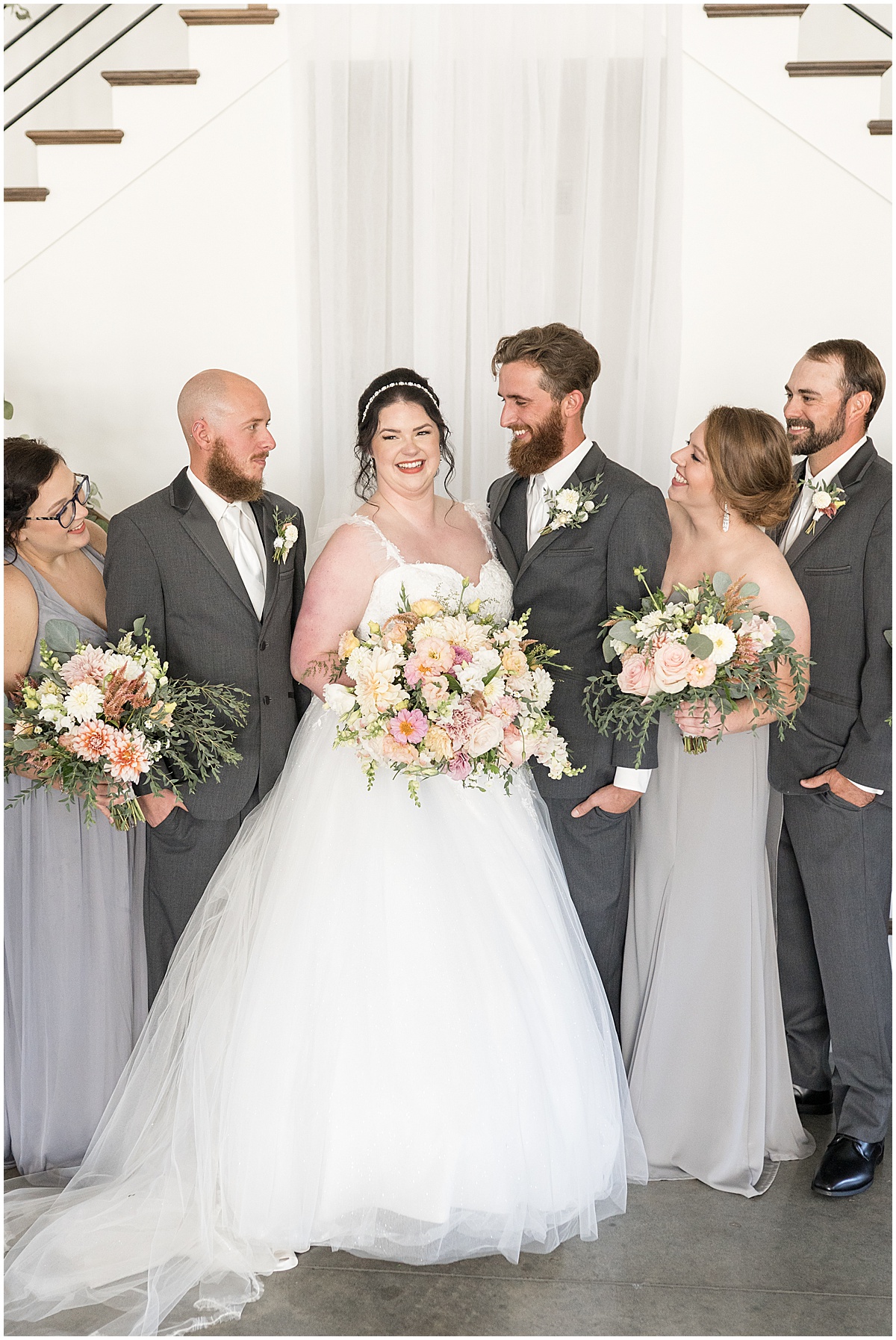 Bridal party looks at bride during pastel wedding at New Journey Farms in Lafayette, Indiana