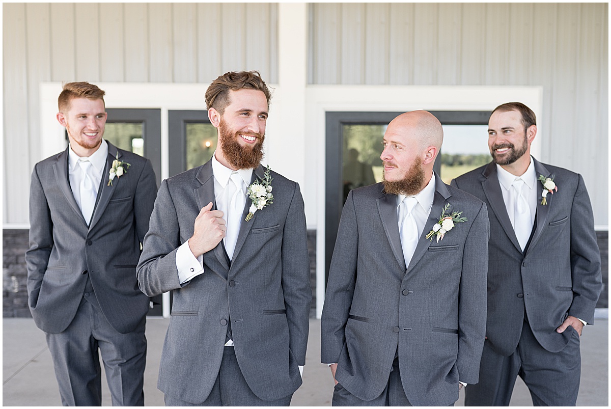 Groom and groomsmen walk during photos at pastel wedding at New Journey Farms in Lafayette, Indiana