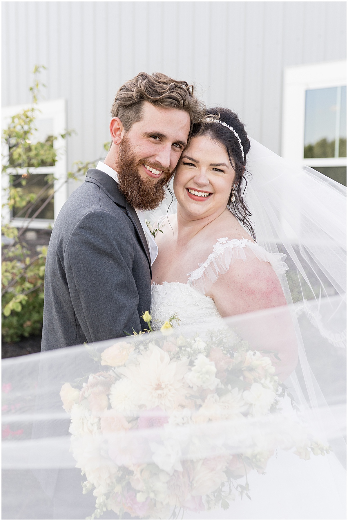 Bride and groom wrapped in veil after pastel wedding at New Journey Farms in Lafayette, Indiana