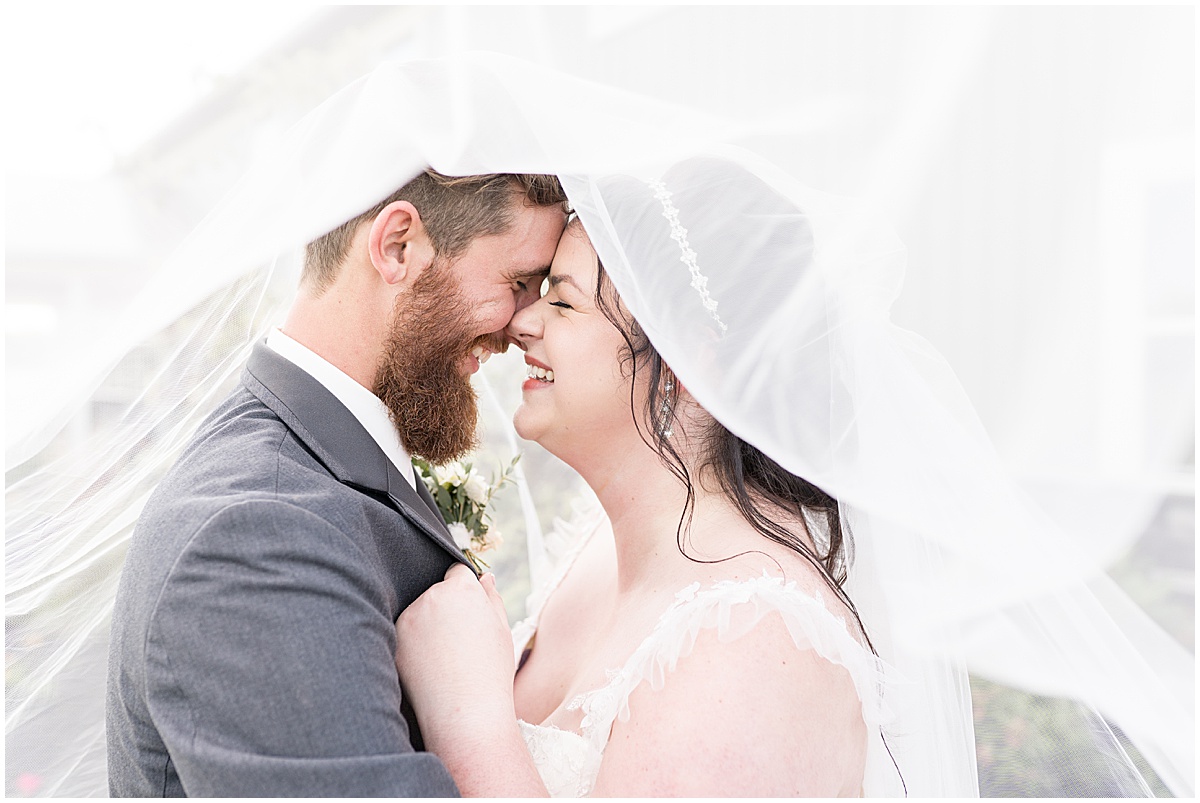 Bride and groom laugh under veil after pastel wedding at New Journey Farms in Lafayette, Indiana