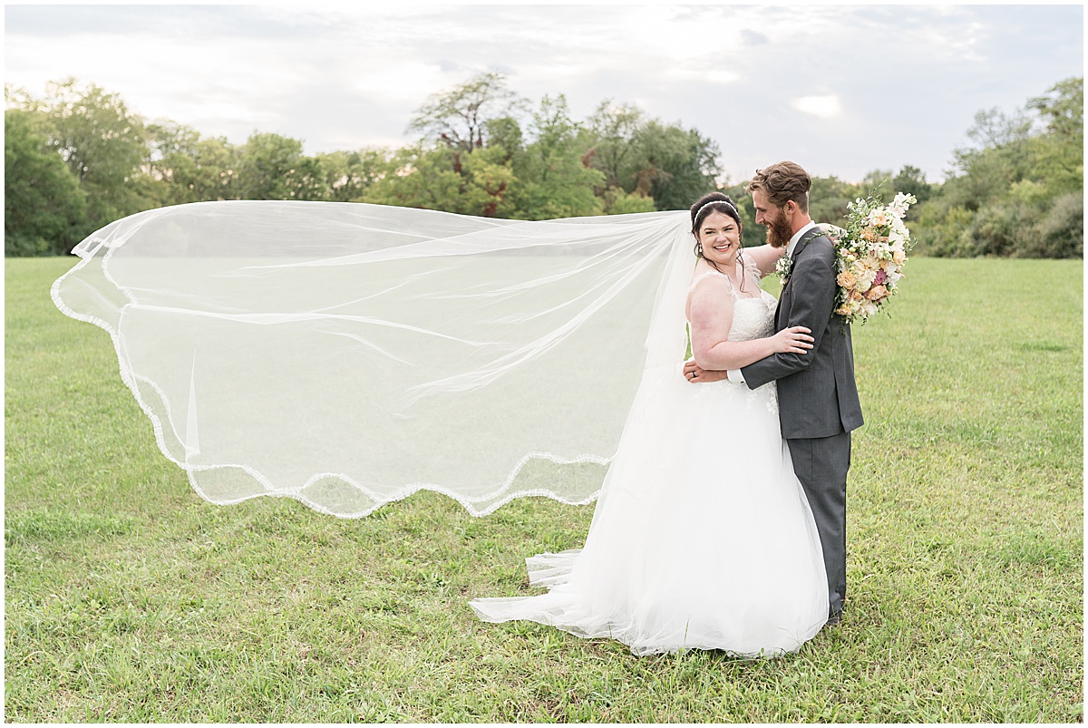 Bride's veil floats in wind after pastel wedding at New Journey Farms in Lafayette, Indiana