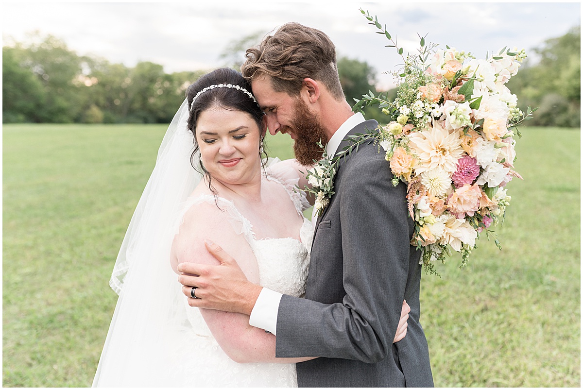 Bride and groom snuggle together afte pastel wedding at New Journey Farms in Lafayette, Indiana