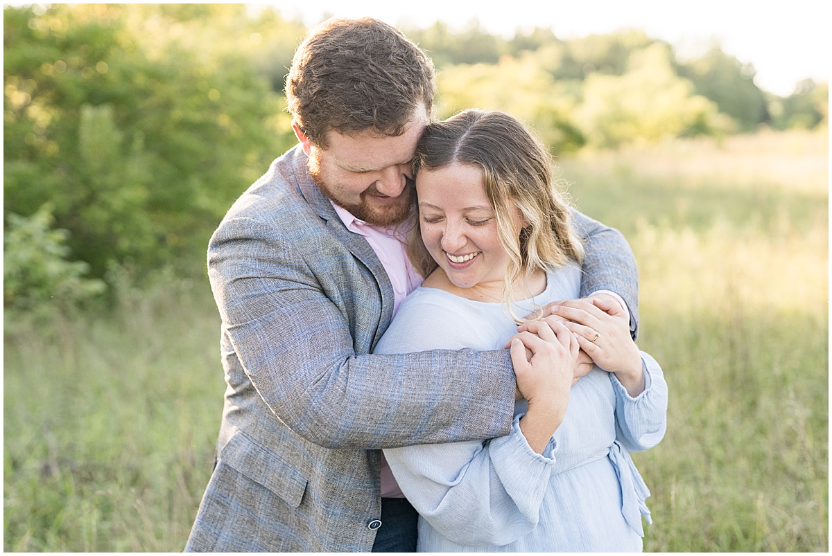 Couple wearing pastels hug during summer engagement photos at Fairfield Lakes Park