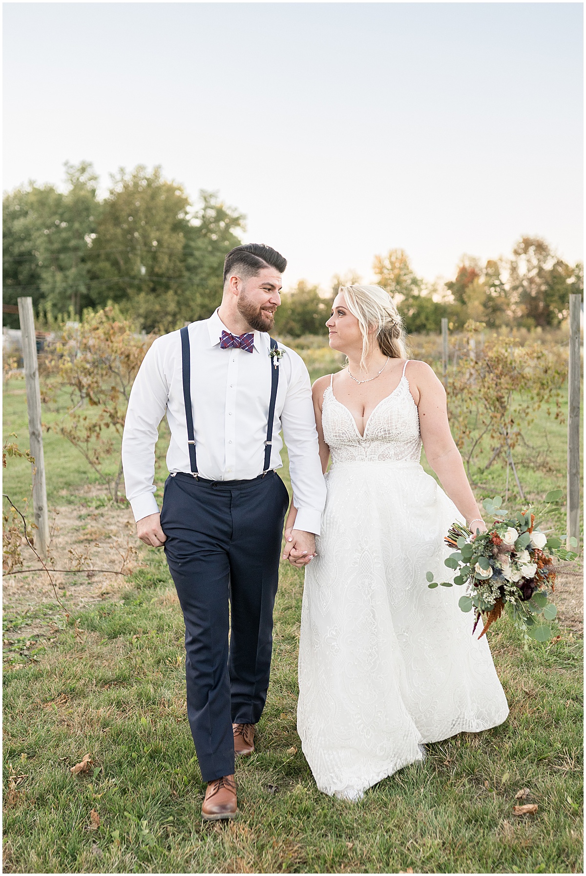 Bride and groom walk through vineyard at Finley Creek Vineyards wedding in Zionsville, Indiana