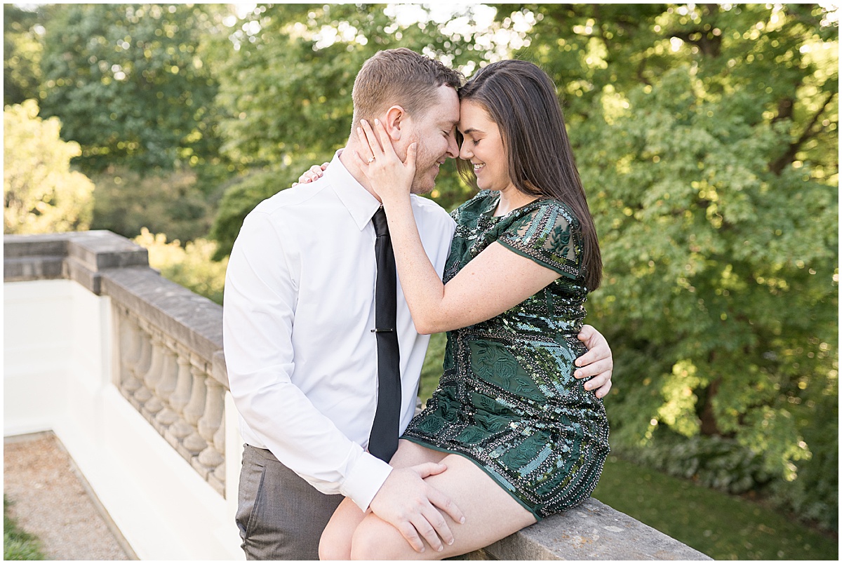 Couple embrace on stone railing at jewel tone engagement photos at Newfields
