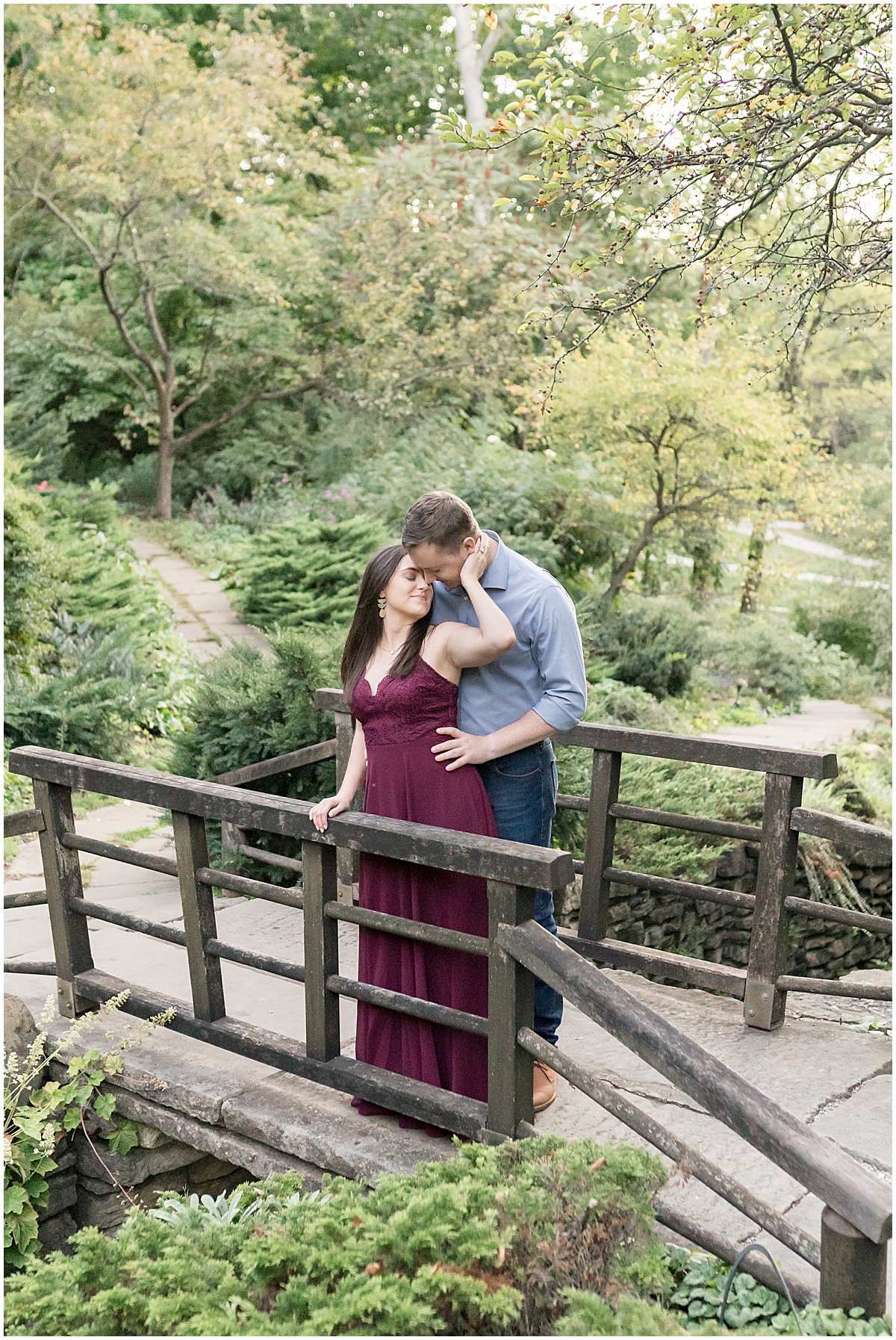 Couple kiss on bridge at jewel tone engagement photos at Newfields