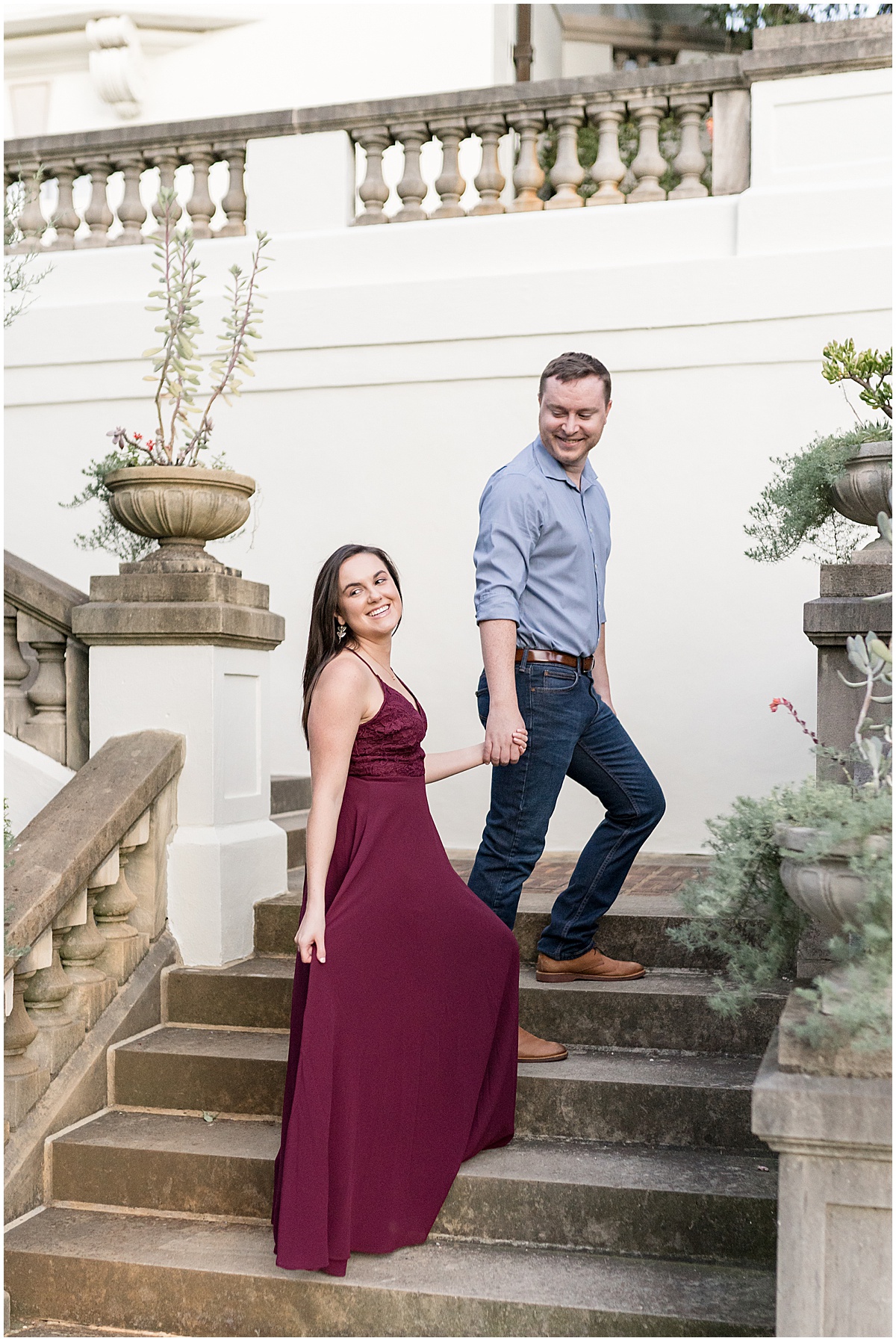 Couple walks up staircase at jewel tone engagement photos at Newfields