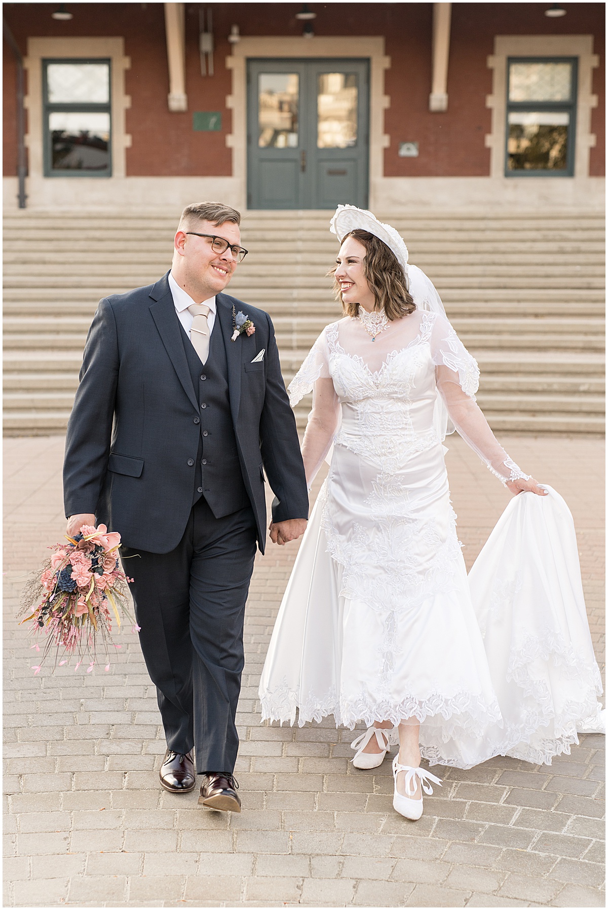 Bride and groom walking in front of train station during wedding photos in Downtown Lafayette, Indiana