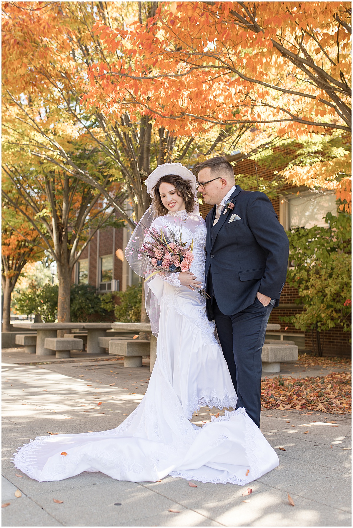 Bride and groom next to orange fall leaves at wedding at St. Thomas Aquina Church in West Lafayette, Indiana