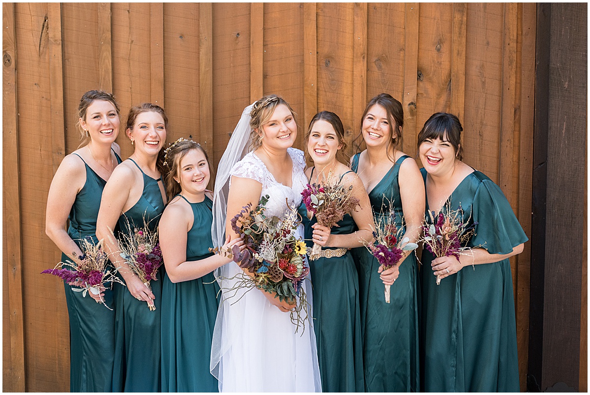 Bride with bridesmaids in teal dresses before fall wedding at 3 Fat Labs in Greencastle, Indiana