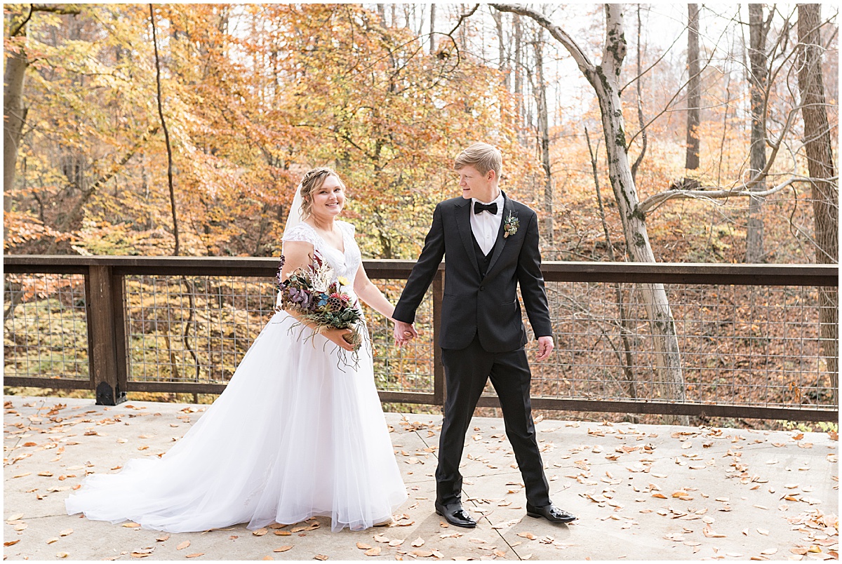 Bride and groom walk in fall leaves after fall wedding at 3 Fat Labs in Greencastle, Indiana